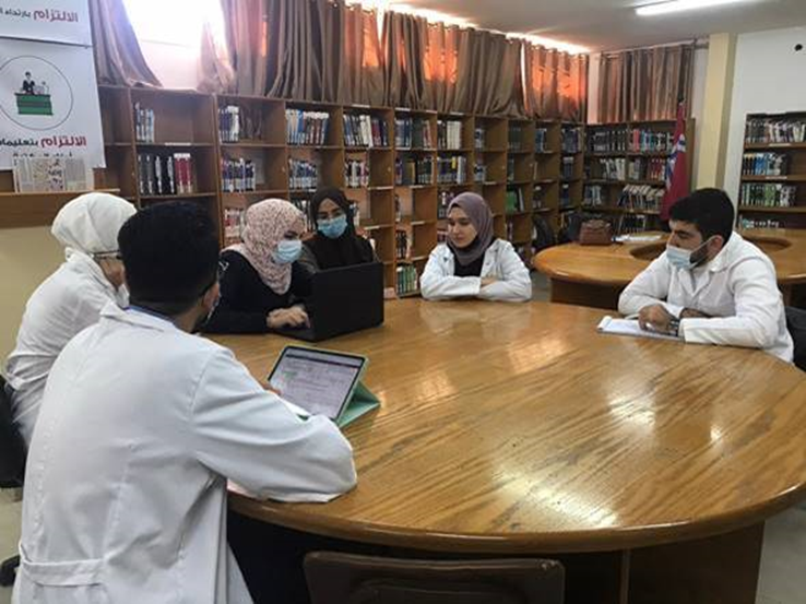 En gruppe med helsepersonell sitter rundt et bord på et biblioteket